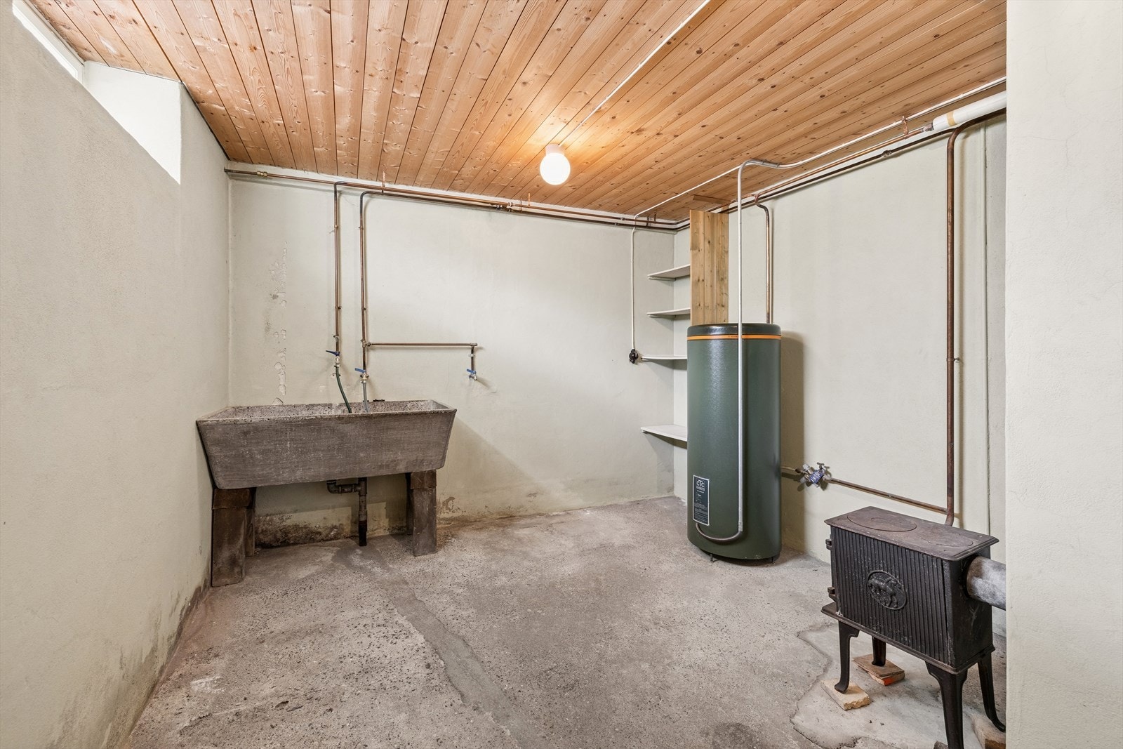 Kjelleren har et rom innredet som vaskekjeller med betonggulv med sluk, en stor vaskekum i betong og opplegg for vaskemaskin. Rommet er ikke godkjent som våtrom. Her står også en liten vedovn, i tillegg til en eldre varmtvannsbereder på 200L. Galleribilde