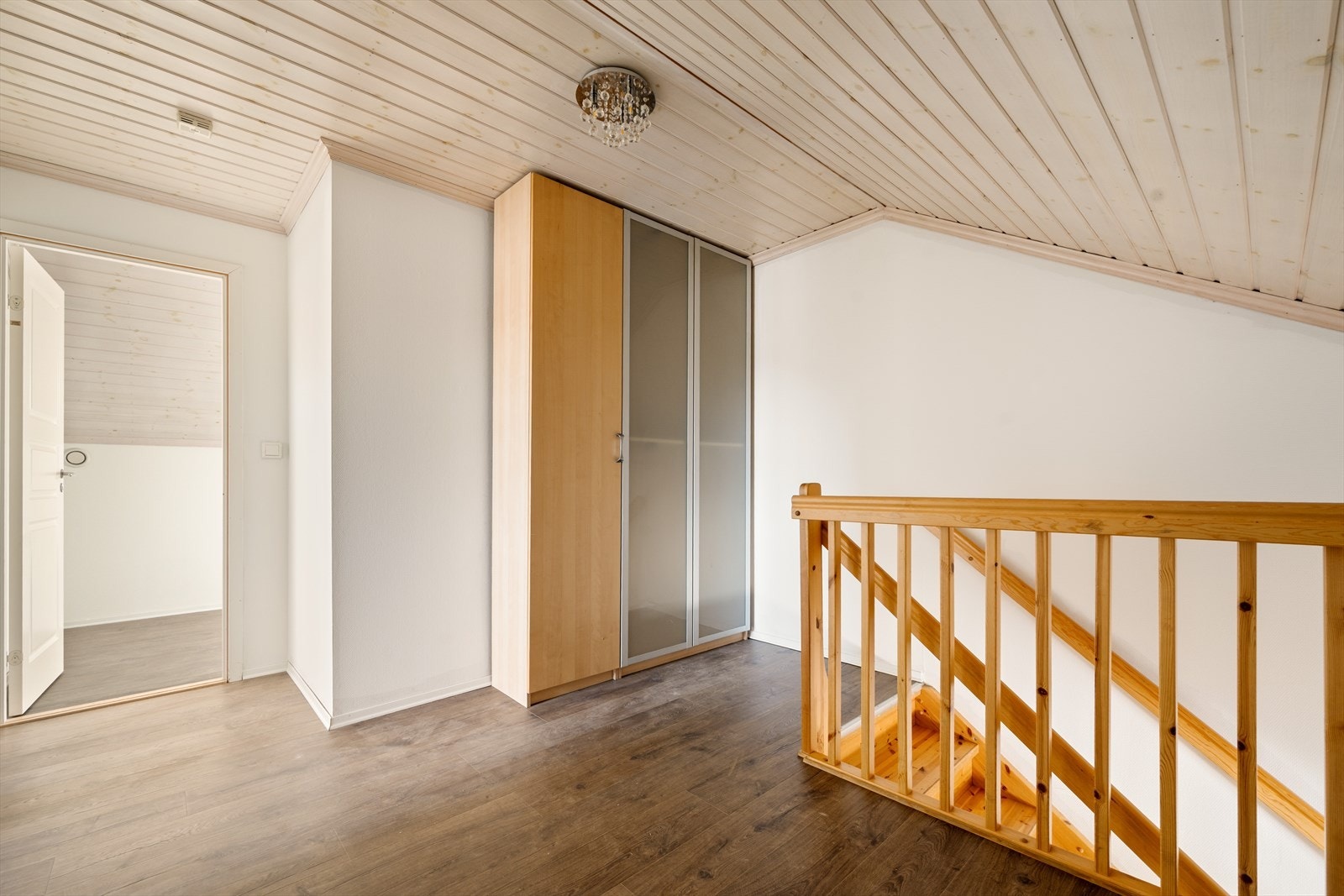 Trappegangen i loftsetasjen fremstår som både lys og funksjonell, med samme slitesterke laminatgulv som gir en helhetlig og moderne følelse gjennom boligen. Her er det god plass til oppbevaring i et stort garderobeskap i varm bjørkefarge. Galleribilde