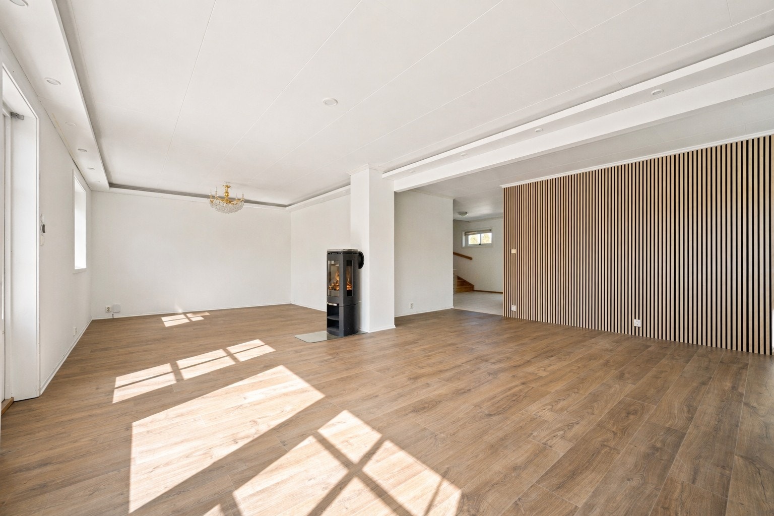 Stuen er utformet i en praktisk L-løsning som gir gode møbleringsmuligheter og en naturlig inndeling mellom sonene. Det slitesterke laminatgulvet videreføres her og skaper en helhetlig og moderne base. Galleribilde