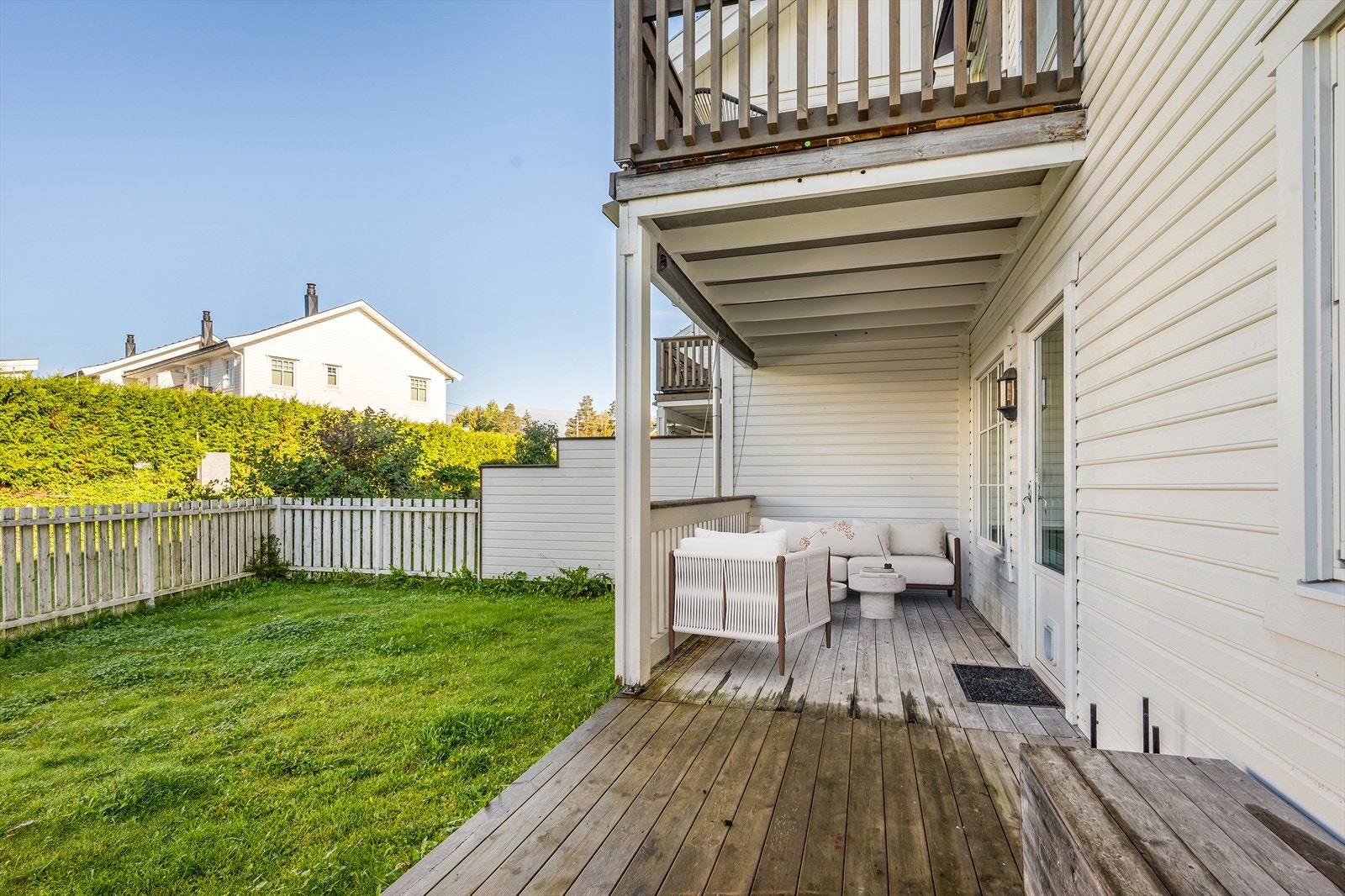 Innbydende markterrasse med delvis takoverbygg fra balkongen over, som gir en lun og skjermet uteplass uansett vær. Her er det god plass til både loungesett og grill - perfekt for avslapning og sosiale sammenkomster. (Digitalt møblert bilde) Galleribilde