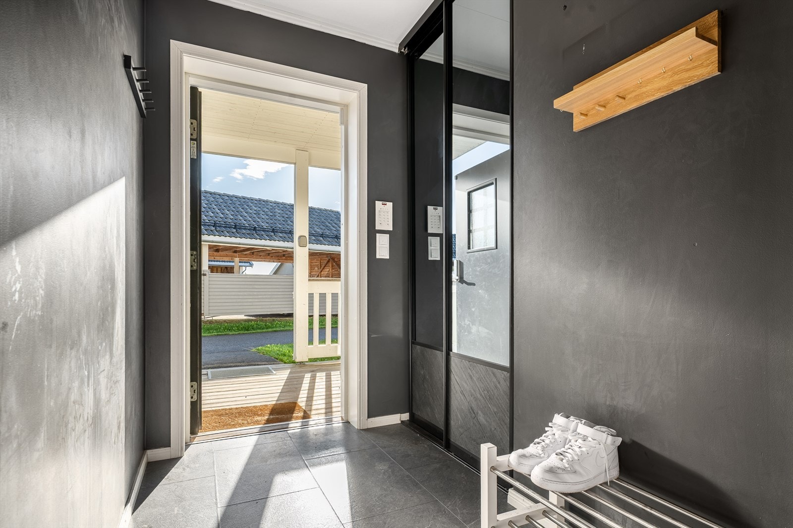 Entréen gir et stilfullt førsteinntrykk med vegger malt i en dempet sort tone som skaper en lun og moderne atmosfære. Her er det god plass til oppbevaring i praktisk skyvedørsgarderobe med speilfronter, som både er funksjonell og romslig. Galleribilde