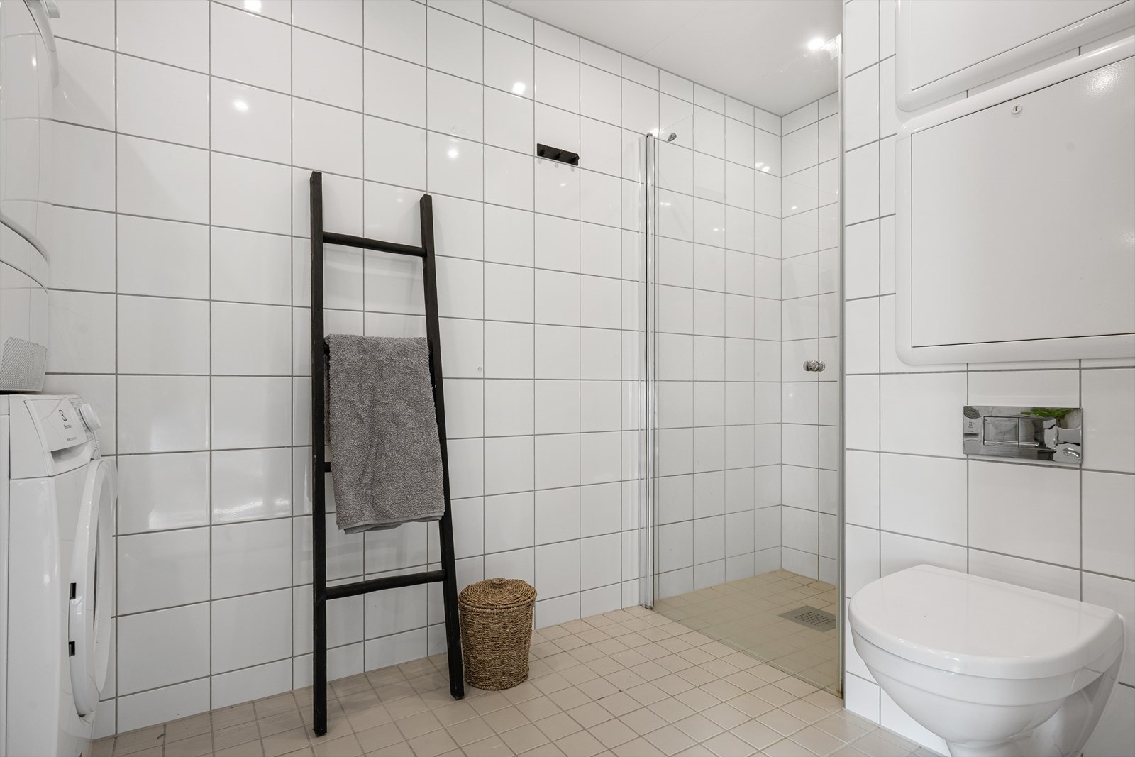 Dusjsonen er etablert i et eget hjørne og avskjermet med dusjdør i herdet glass, noe som gir et ryddig og luftig preg. Utstrakt bruk av downlights i himling. Galleribilde