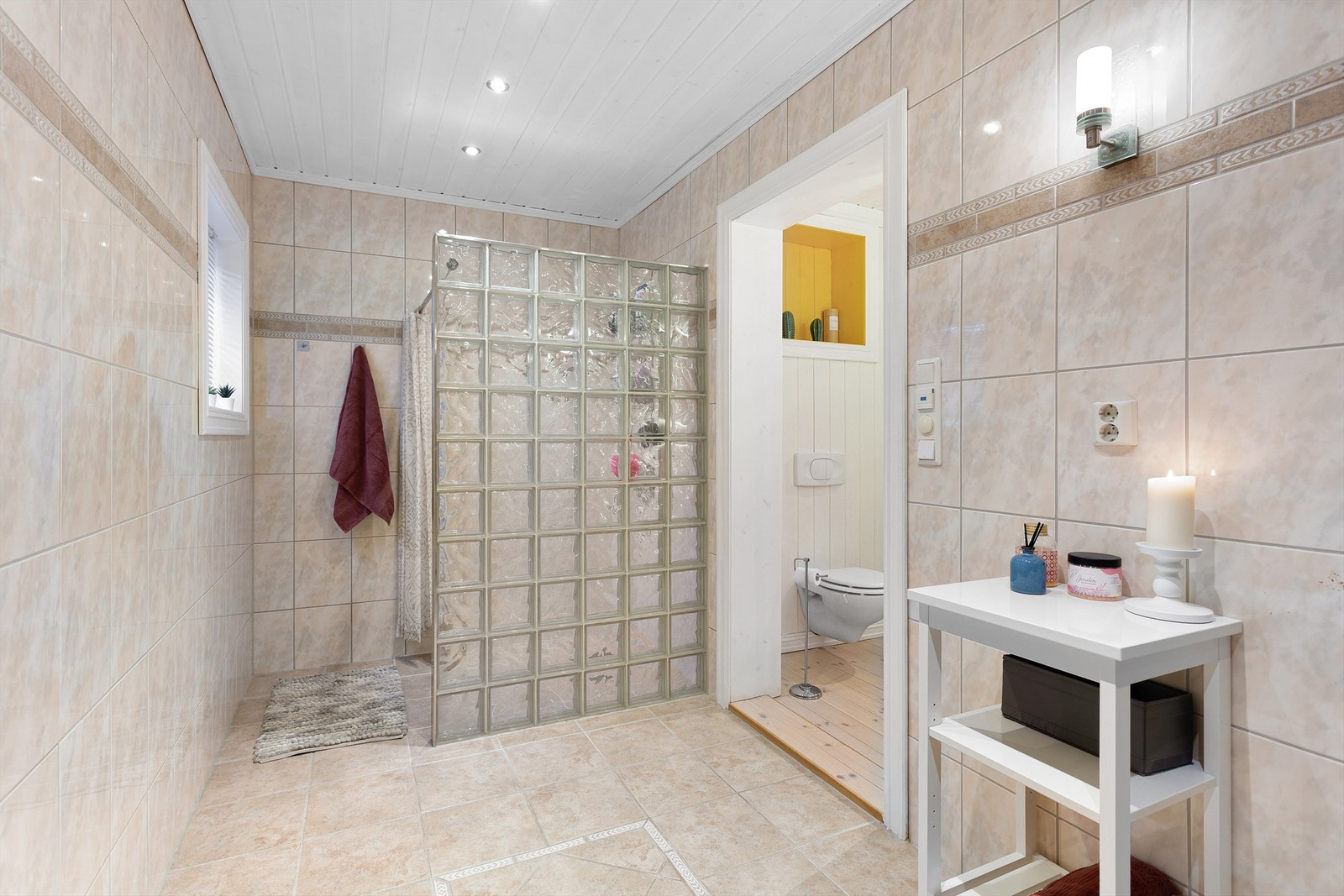 Den andre delen av badet har flislagt gulv og flislagte vegger. Egen dusjdel med gulvvarme og badekar. Galleribilde
