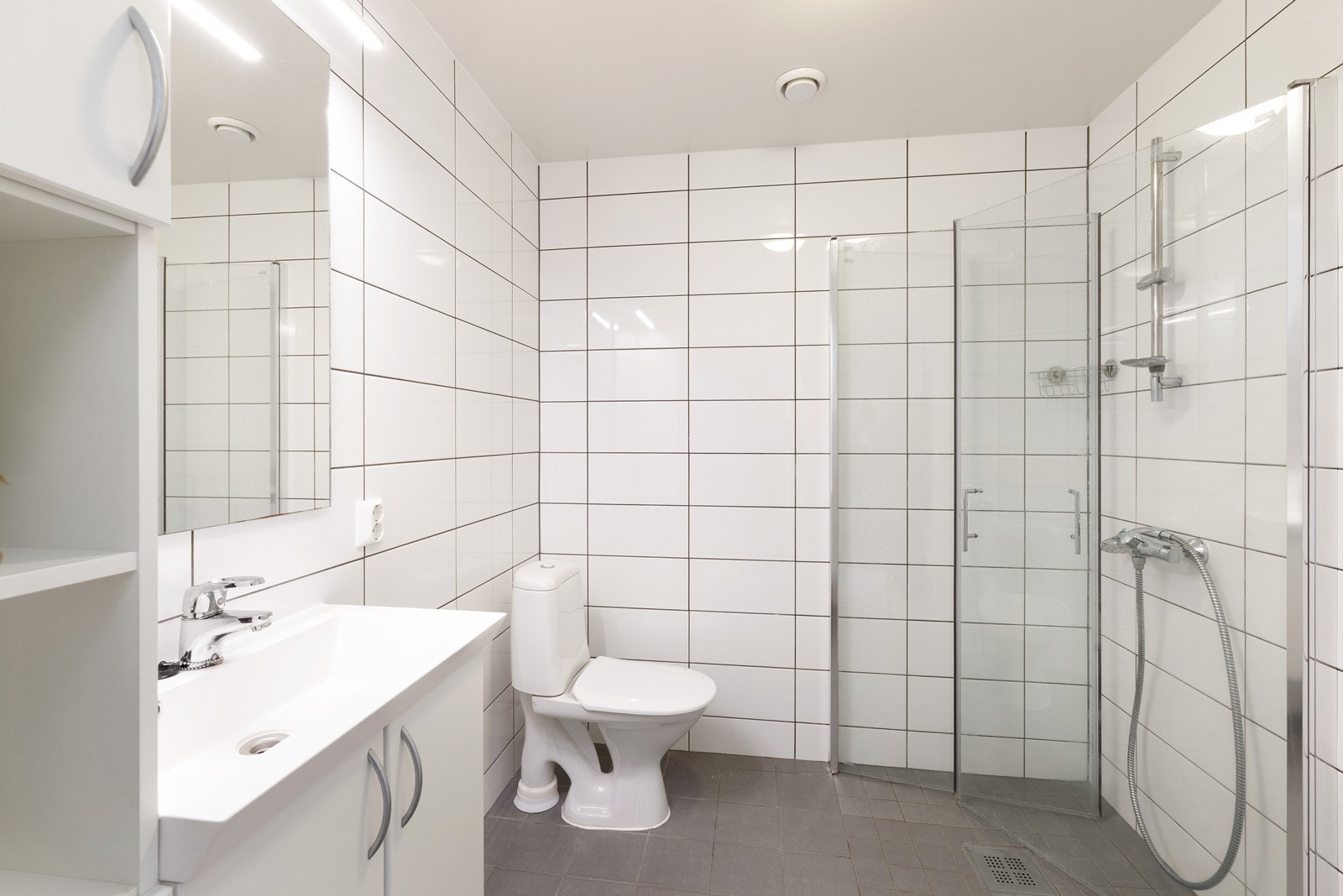 Helfliset bad med varmekabler. Badet er utstyrt med skap, heldekkende servant med underskap, toalett og dusjhjørne. Galleribilde
