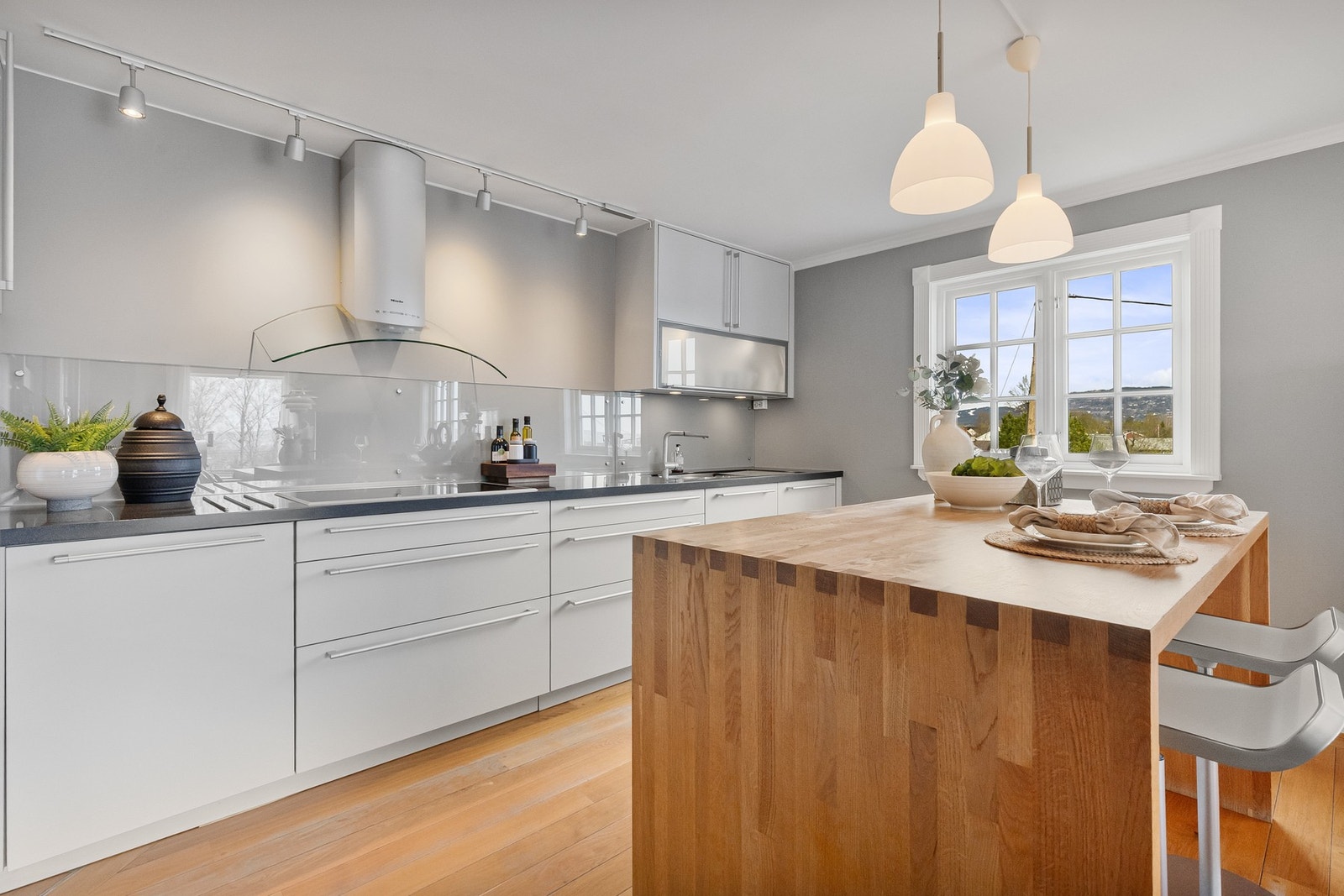 Kjøkkeninredning fra Poggenpohl med grå fronter og mørkere benkeplater i Corian samt kjøkkenøy i varmt treverk. Galleribilde