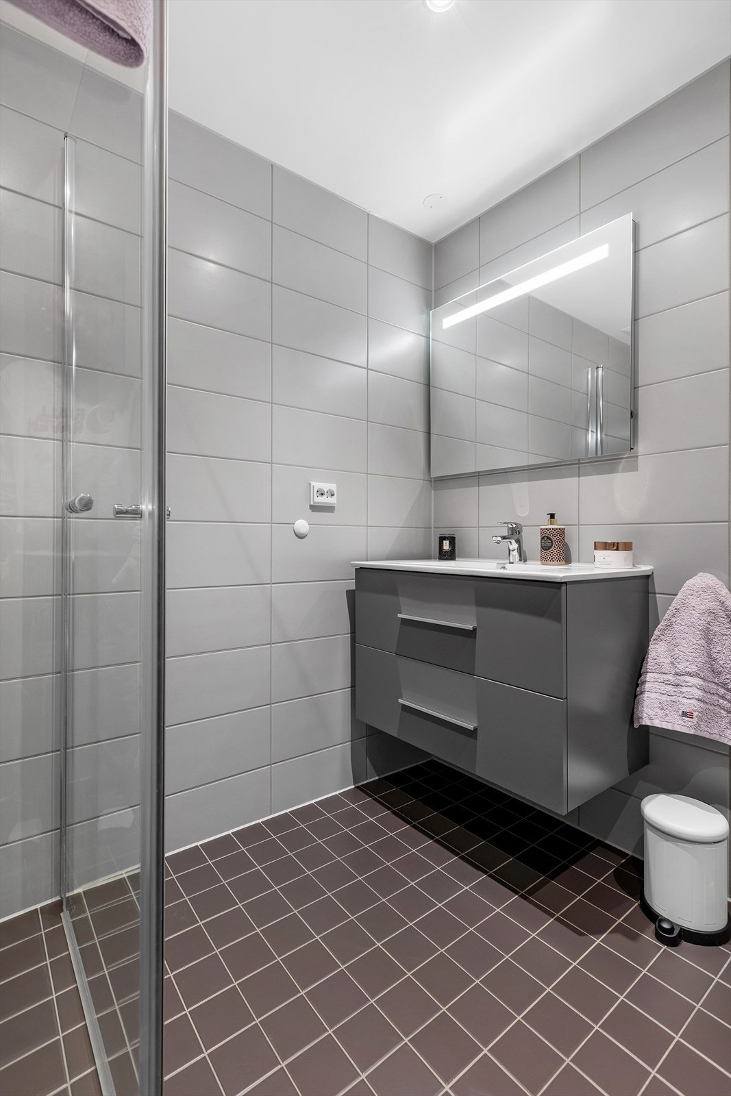 Her på badet er det vannbåren gulvvarme. Innredningen består av servant, vegghengt toalett og dusjhjørne med innfellbare dører. Galleribilde