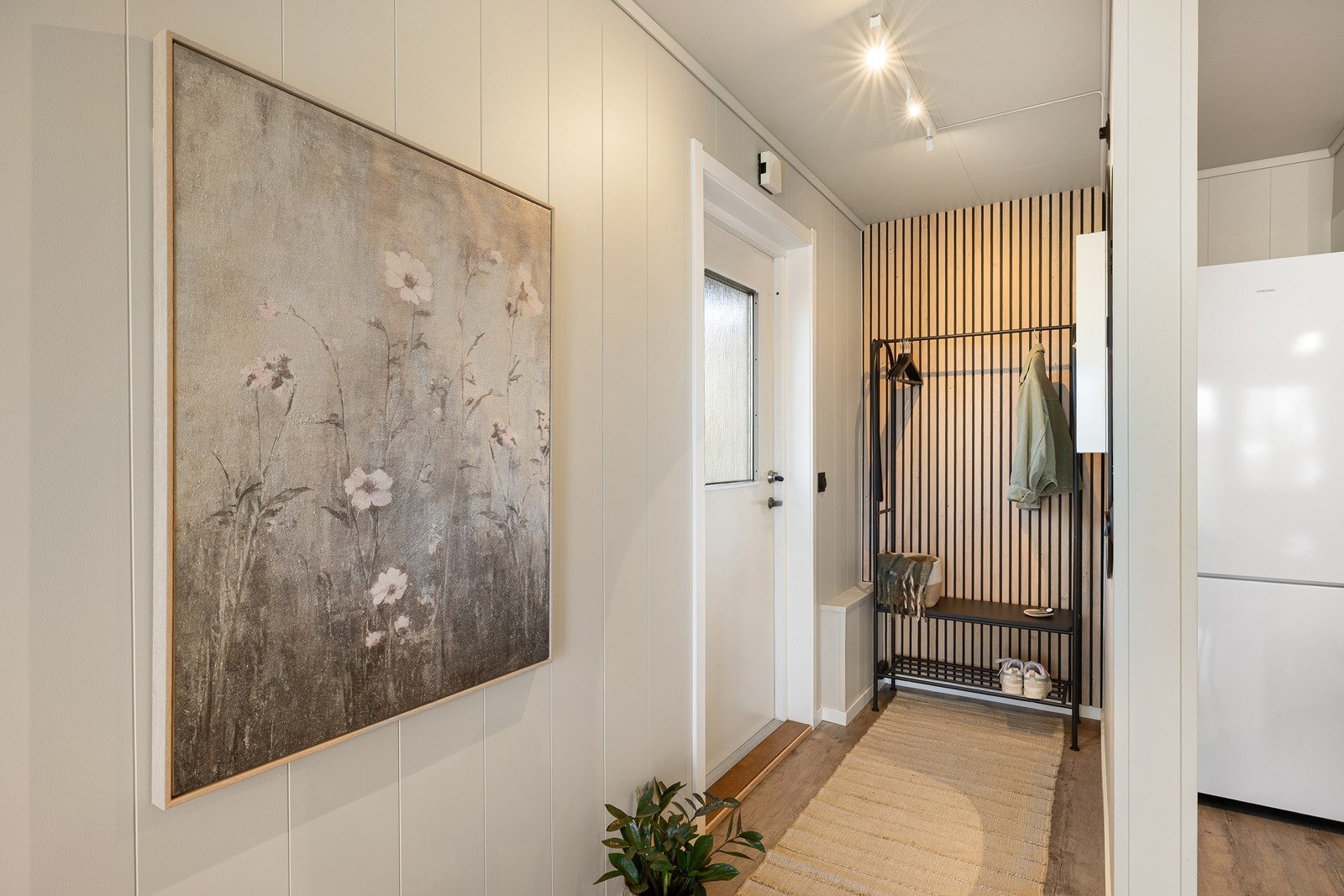 Leiligheten har en lys og innbydende entré med praktisk plass til garderobeløsning. Her er det nylig montert en stilren spilevegg som gir et moderne førsteinntrykk. Galleribilde