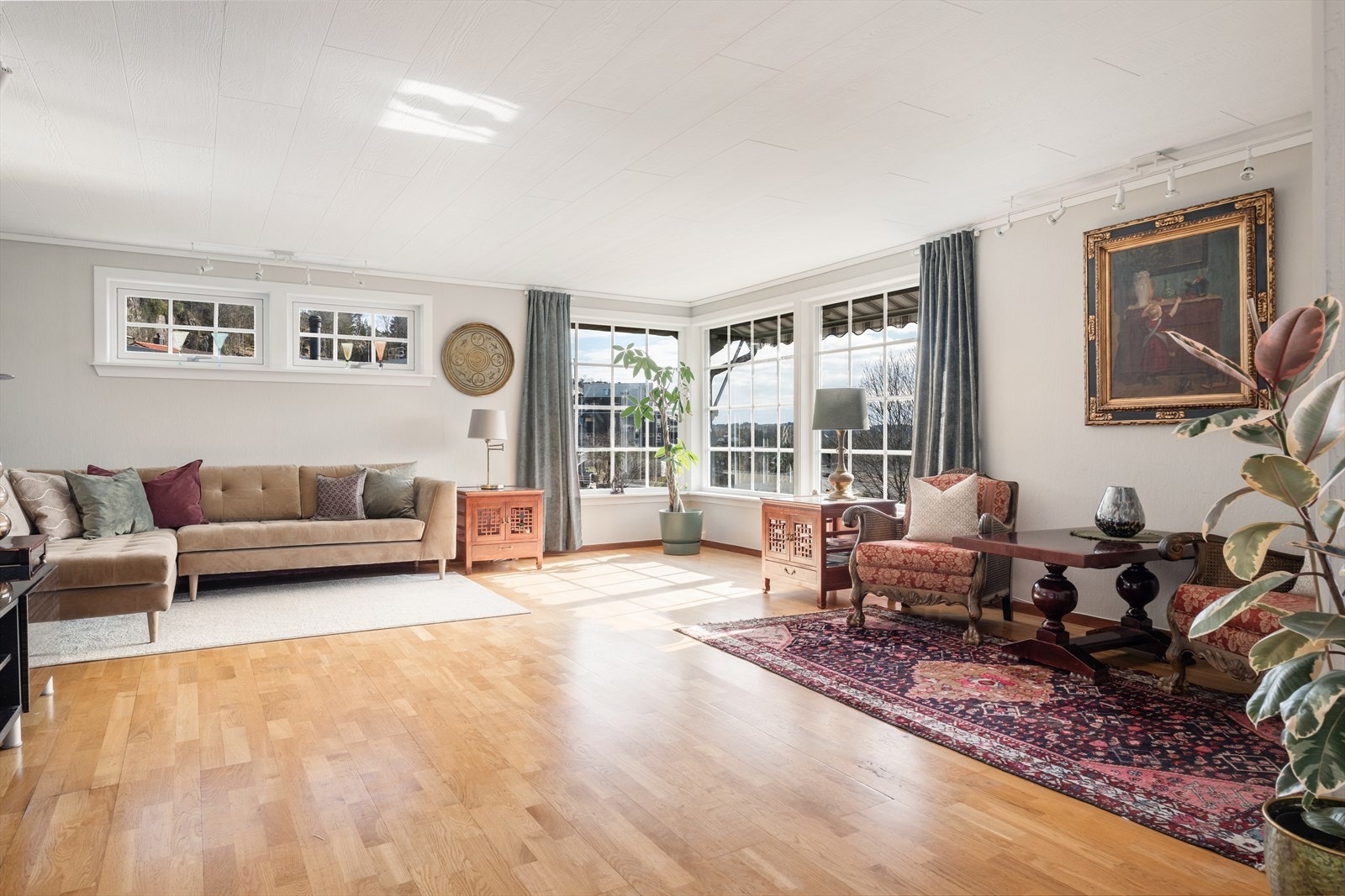Overflatene i stuen består av tre-stavs parkett på gulv, malt strie og malte panel på vegger, og malt panel i himling. Galleribilde