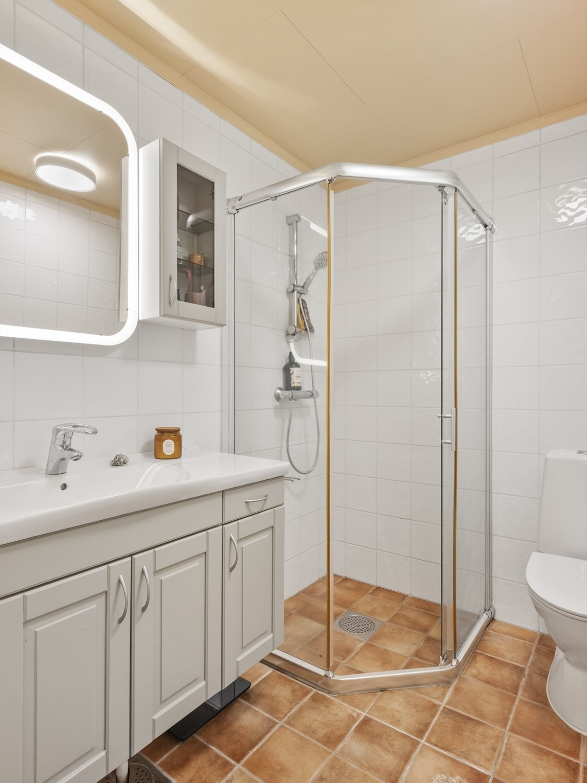 Badet i underetasjen er flislagt og utstyrt med dusjkabinett og servant med underskap. Galleribilde
