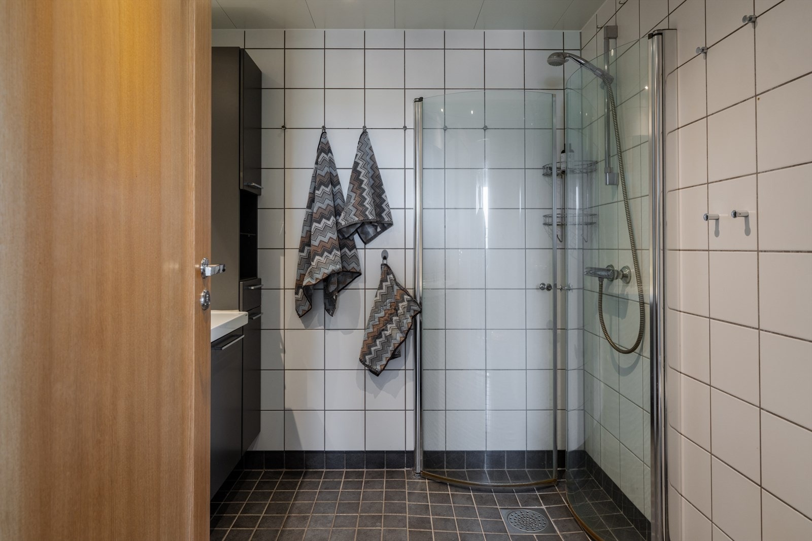 Helflist bad med dusjhjørne med innfellbare glassdører som frigjør gulvplass. Galleribilde