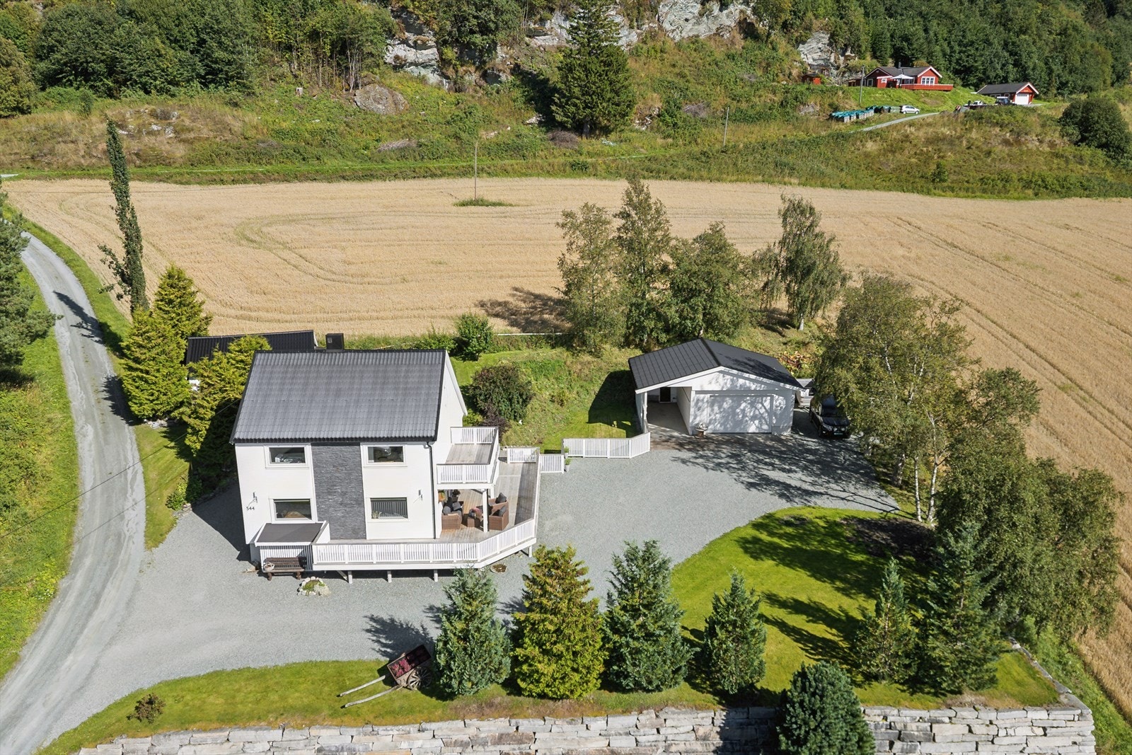 Stor, gruset gårdsplass med rikelig parkeringsplass i tillegg til garasje og carport. Galleribilde