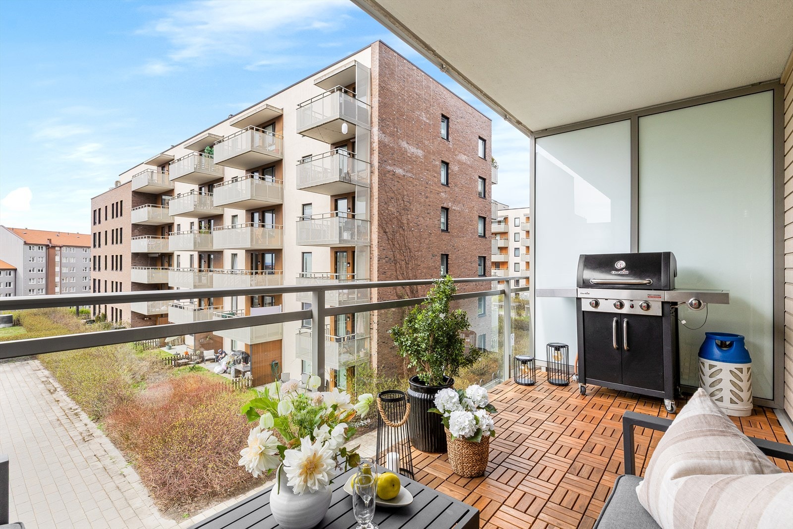 Overbygd sydvestvendt balkong på ca. 9 m² med tremmegulv, utebelysning, strømuttak og glassrekkverk. Galleribilde
