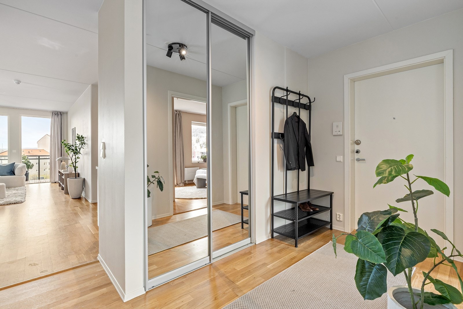 Innbydende entré byr på lyse vegger, parkettgulv og god plass til oppbevaring i skyvedørsgarderobe med speilfronter Galleribilde