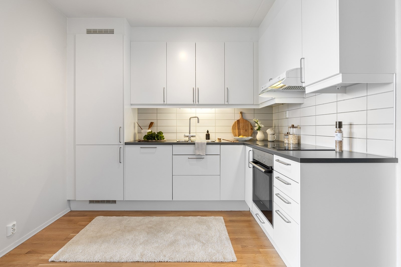 Takhøy innredning med glatte hvite fronter og laminat benkeplate gir god lagringsplass. Galleribilde
