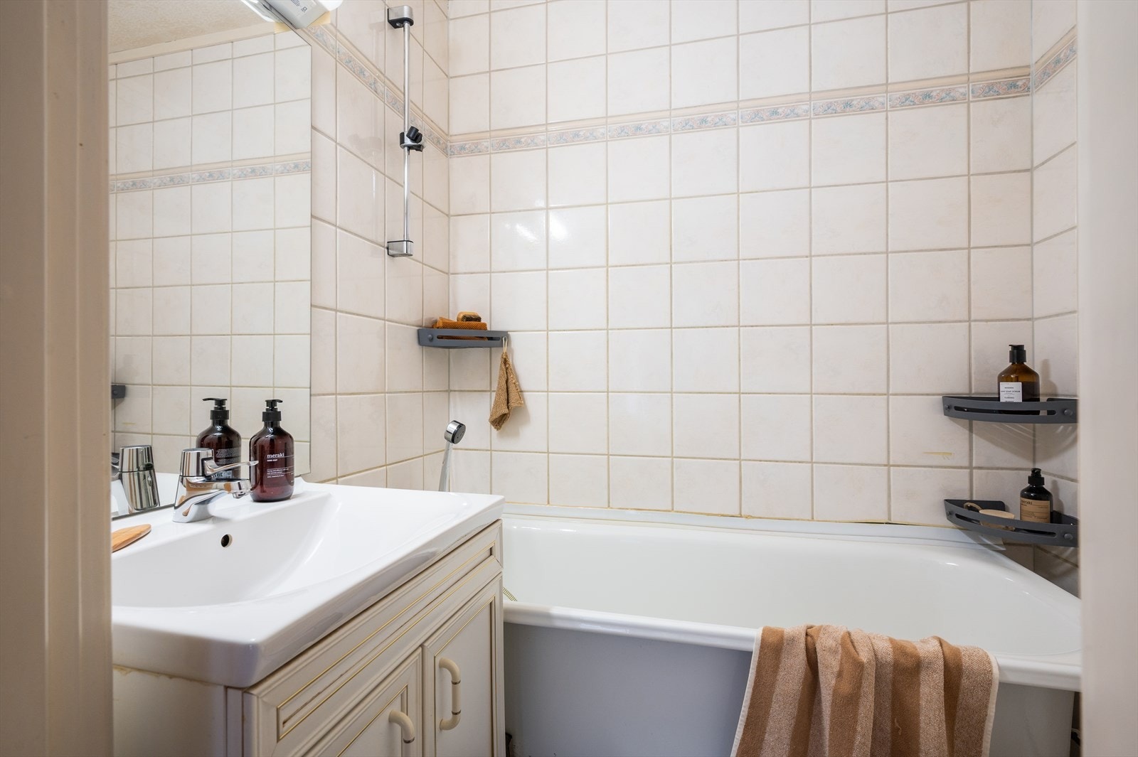 Badet er innredet med gulvstående toalett, servant med underskap samt badekar med dusjløsning. Galleribilde