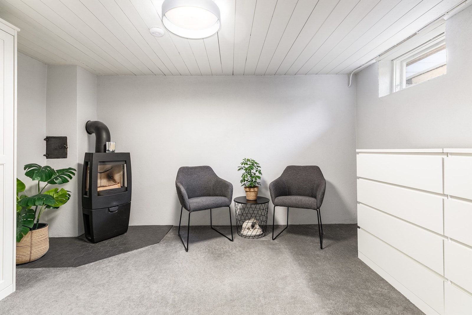 Rommet innenfor badet benyttes som stue, men er ikke omsøkt bruksendret eller godkjent for varig opphold. Vedovn ble montert i 2018, teppe og fliser ble samtidig lagt på gulvet. Galleribilde