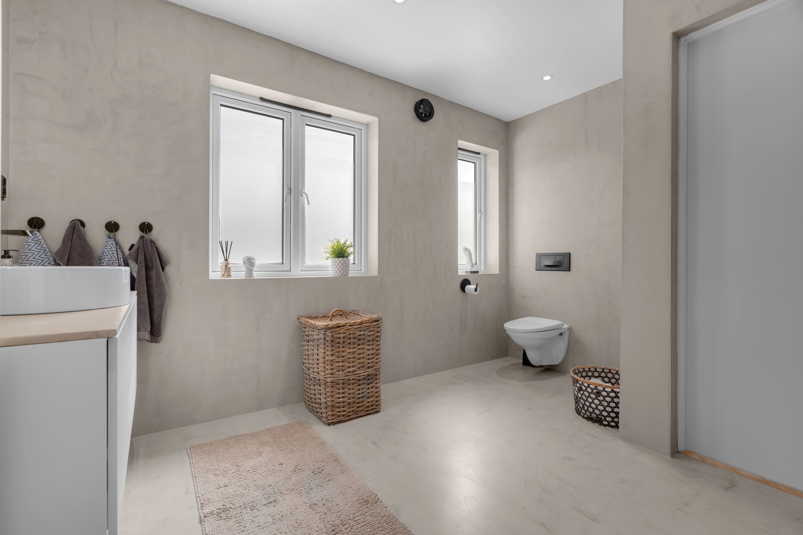 Badet er lyst og lekkert med flere sorte detaljer og vegghengt toalett. Galleribilde
