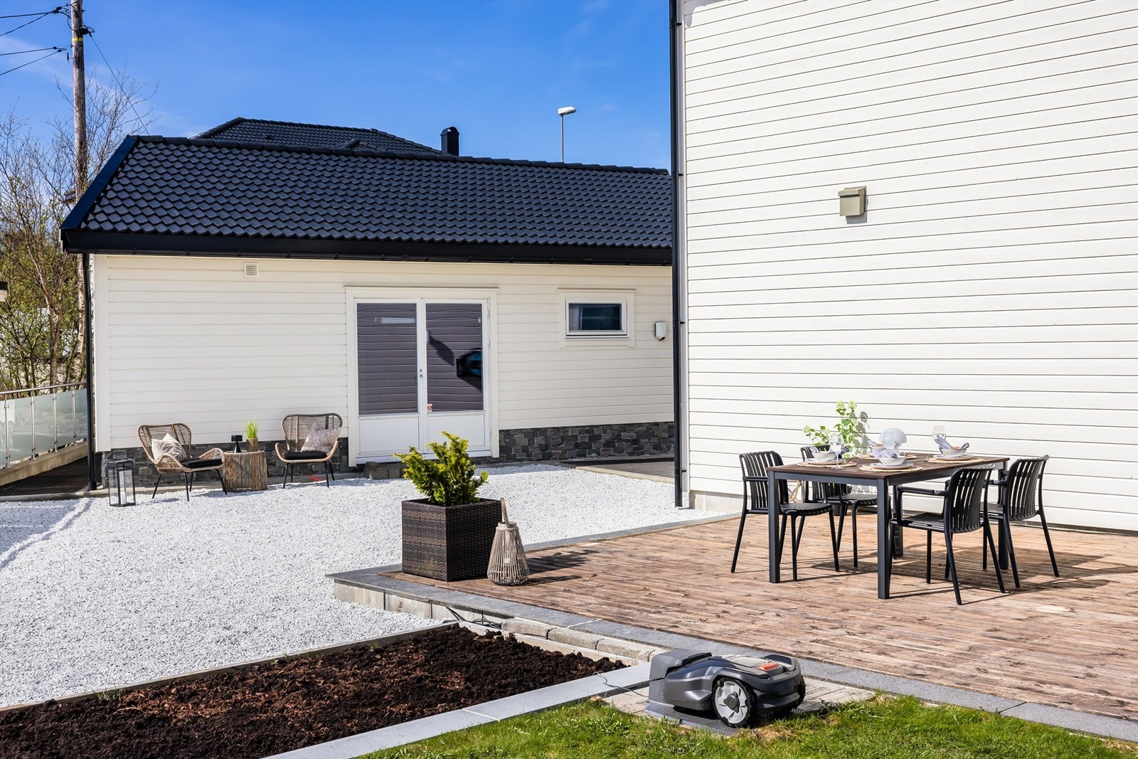 Tomten er pent opparbeidet med en kombinasjon av plen, treterrasser og gruslagte områder. Galleribilde