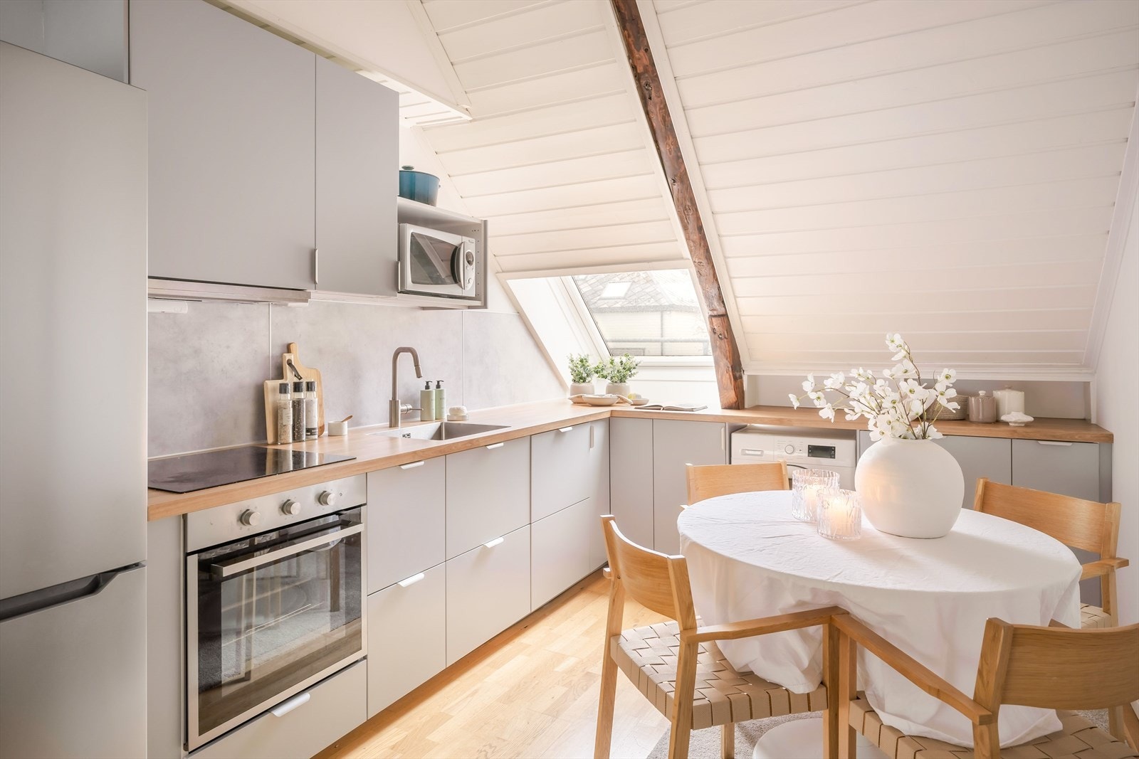 Det lekre kjøkkenet fra 2023 er tilbaketrukket i rommet og har en tidløs innredning med grå slette fronter og en lysere laminert benkeplate. Galleribilde