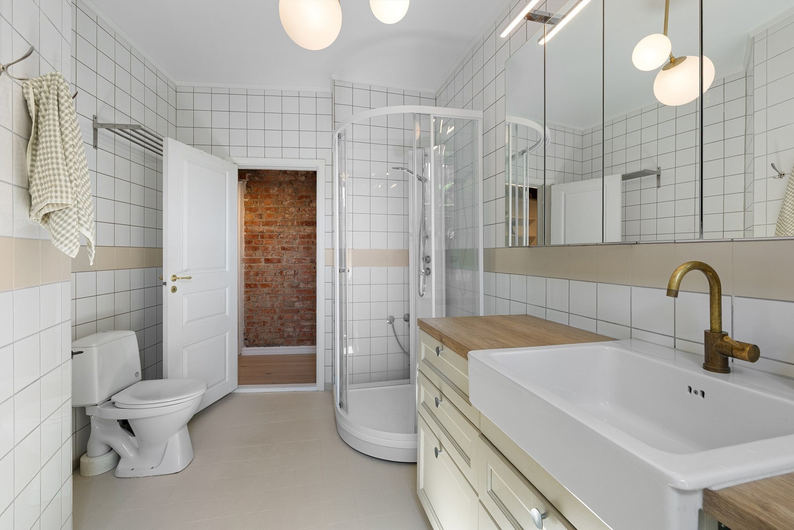 Badet er innredet med nedfelt servant i innredning med speilskap og belysning over. Det er ellers installasjoner med gulvstående toalett og dusjkabinett. Galleribilde