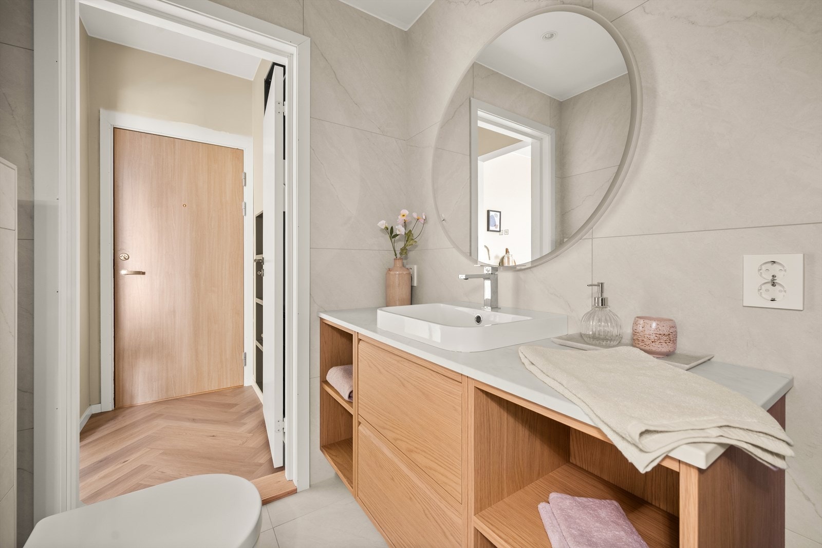 Badet er utstyrt med vegghengt toalett med skjult sisterne, dusjhjørne innfellbare dusjvegger av glass og baderomsinnredning med skuffer, servant på laminatplate med ettgreps blandebatteri. Galleribilde