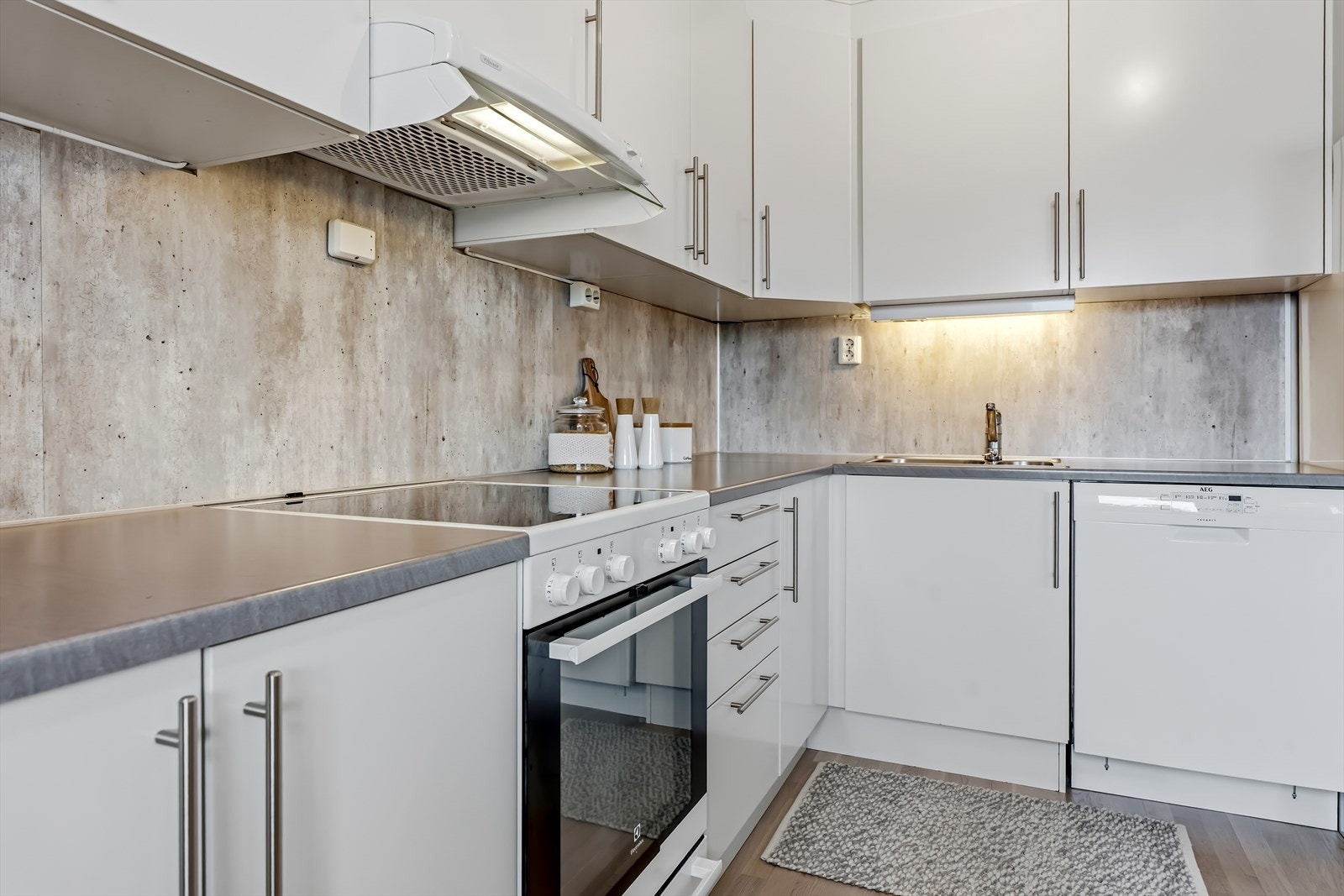 Kjøkkeninnredning med slette fronter og laminert benkeplate. For ekstra trygghet er det installert komfyrvakt over kokesonen og automatisk vannstopp i benkeskap. Galleribilde