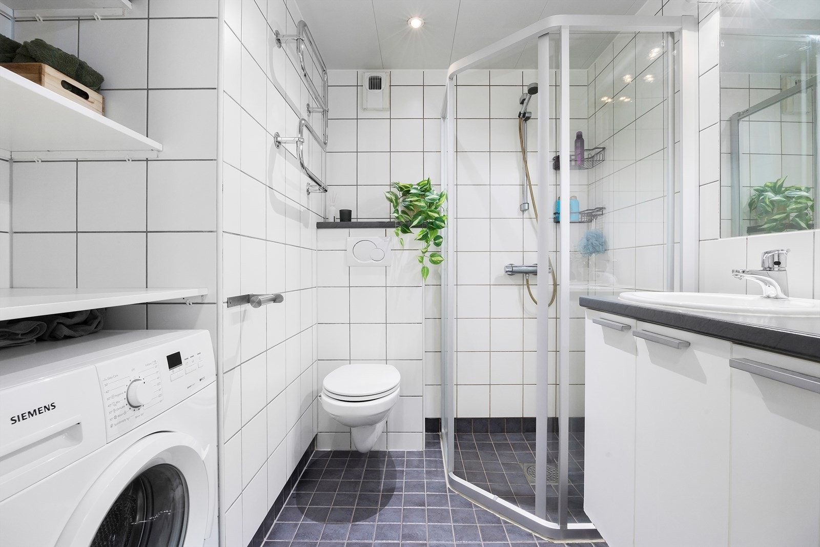 Pent og funksjonelt bad fra byggeår med flislagte overflater på gulv og vegger. Badet har en praktisk planløsning med servantskap, benkeplate, nedfelt servant og speil over servant. Galleribilde