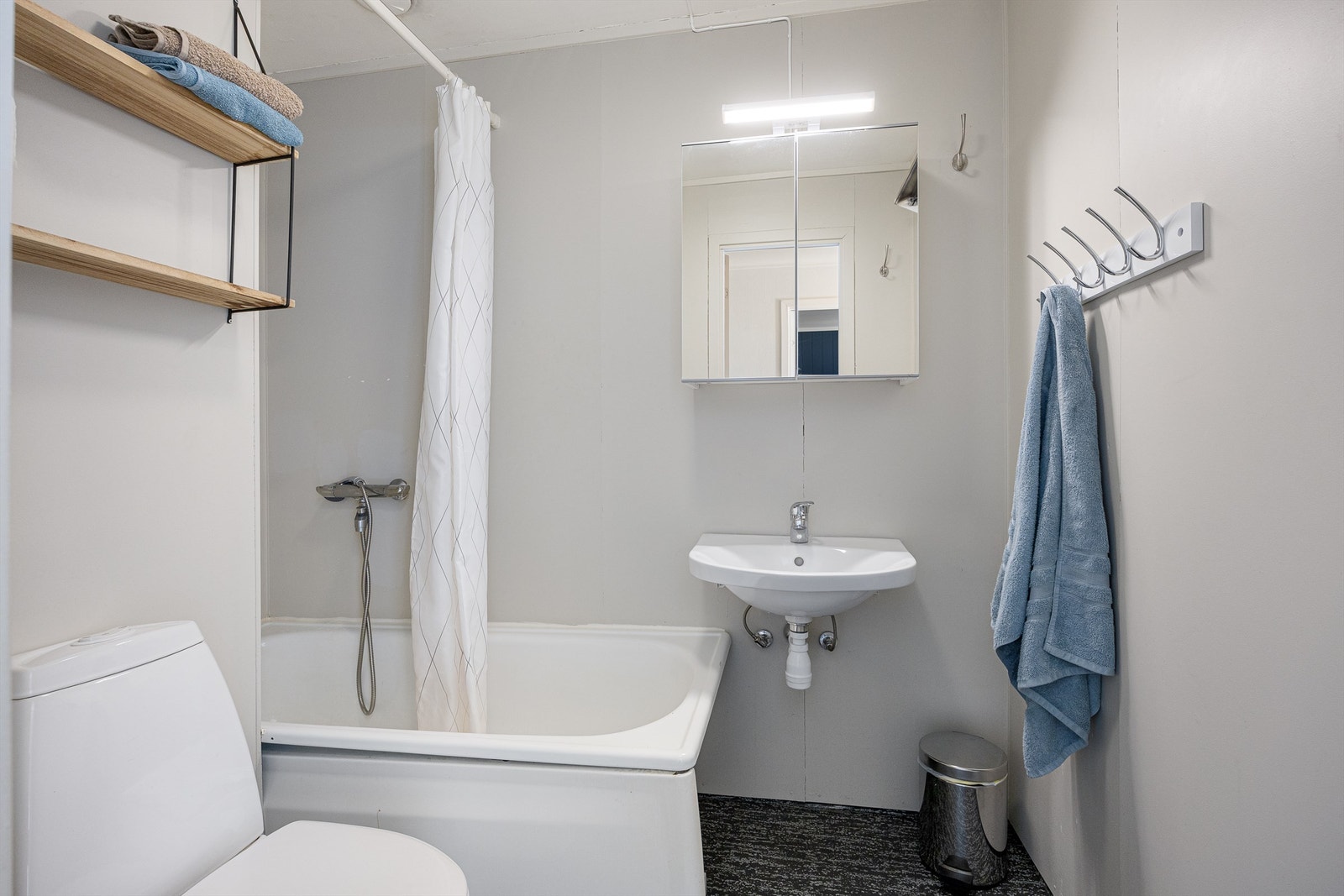 Badet er utstyrt med badekar, veggmontert servant, speilskap og toalett. Galleribilde