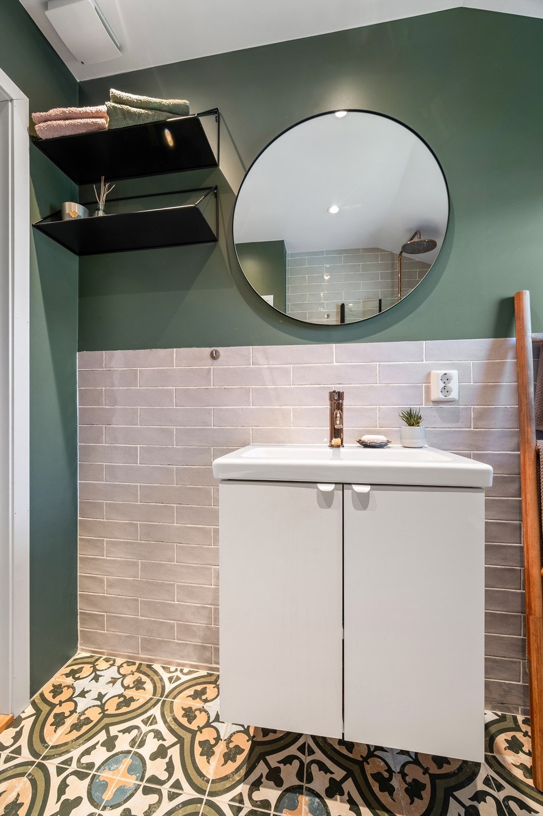 Badet er innredet med veggmontert toalett, dusj på gulv med innfellbare glassdører og servant med underskap, med speil montert over. Galleribilde