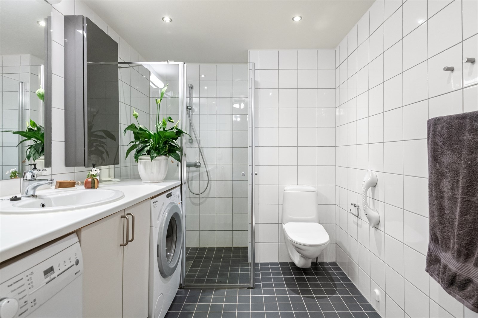 Badet som fremstår som lyst og pent med flislagte overflater, downlights i himling og gulvvarme. Galleribilde