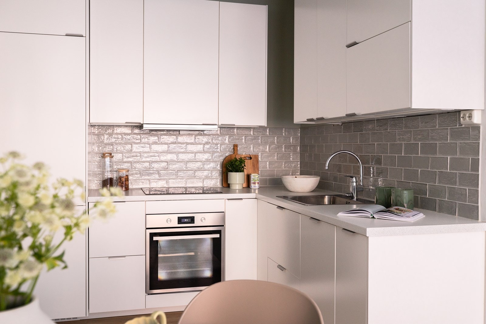Tidsriktig innredning fra IKEA med lyse, glatte fronter, flislagt på veggen over kjøkkenbenken og benkeplate i laminat. Galleribilde