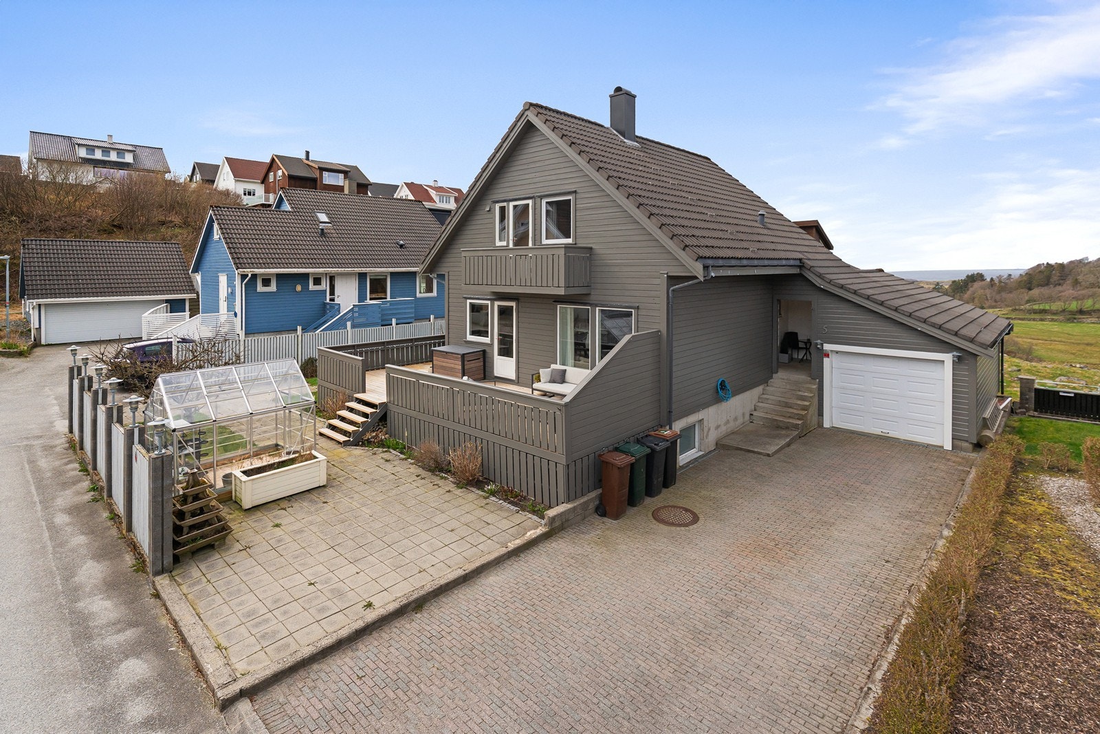 På tomten er det også terrasser, platting samt et lite drivhus som medfølger i handelen. Galleribilde