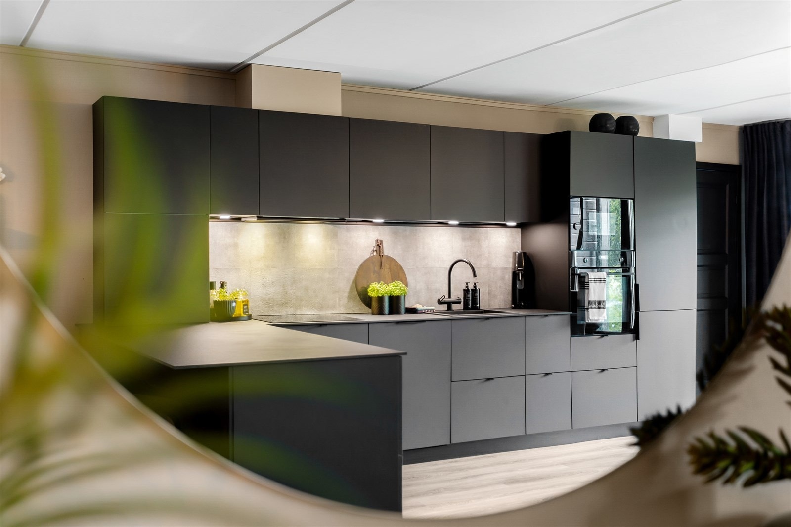Moderne detaljer som kitchenboard over benken og sort ett-greps blandebatteri. Galleribilde