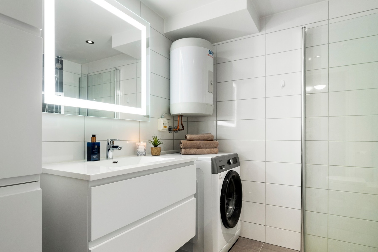 Stilrent flislagt bad av moderne standard. God plass til vaskemaskin og møblement med lagring. Galleribilde