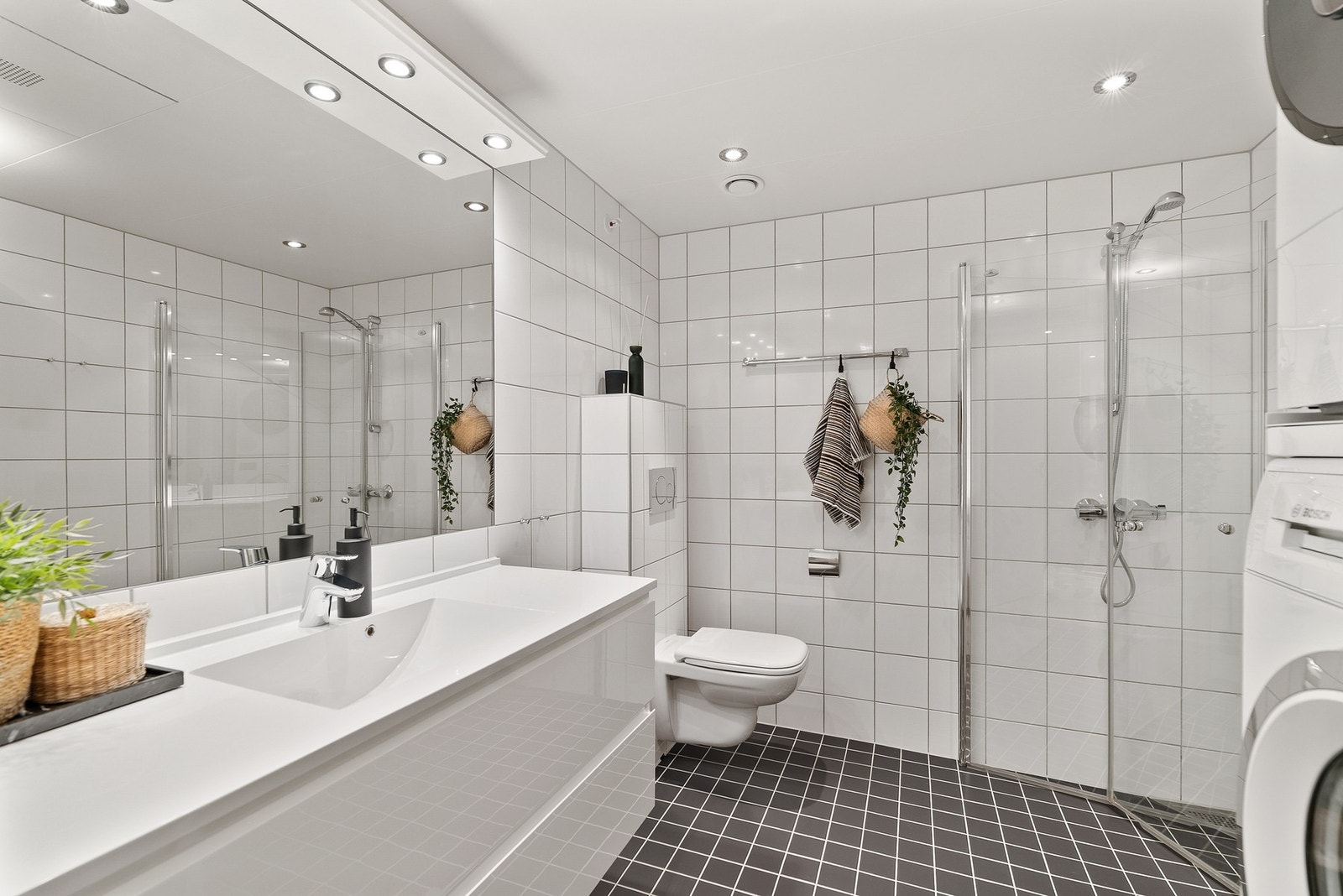 Bad nr. 1 med tidløse fliser, downlights og varmekabler i gulv. Opplegg for vaskemaskin/tørketrommel. Galleribilde