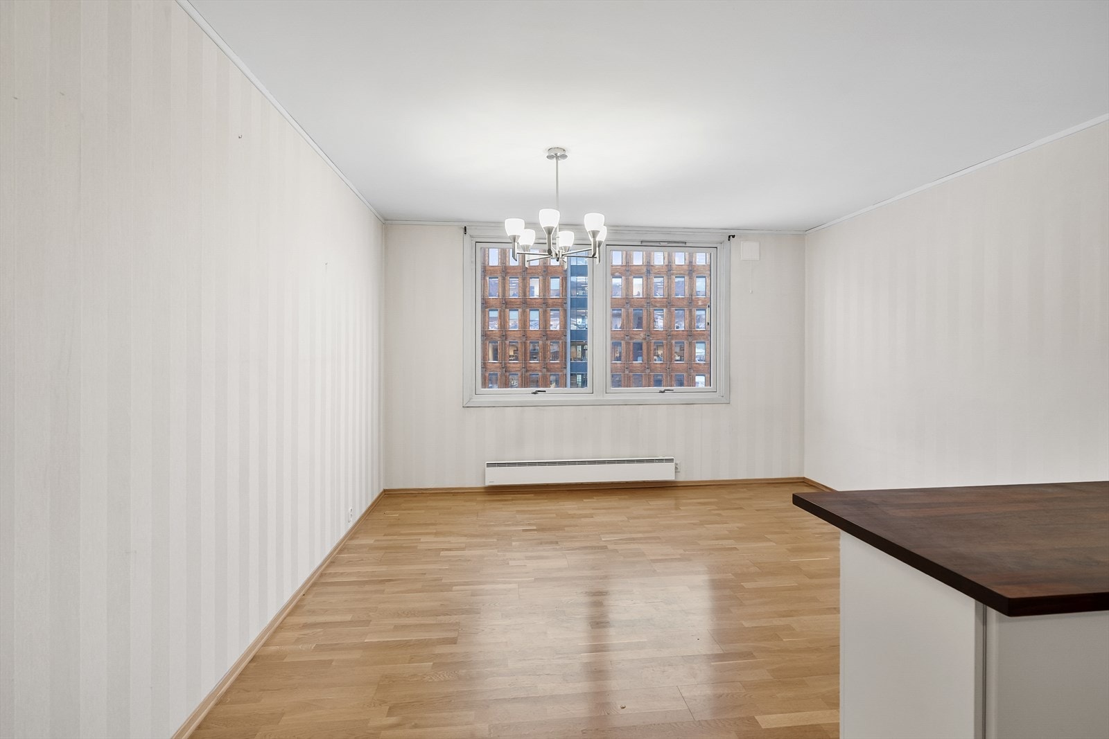 Rommet har parkettgulv, lyse overflater og to store vinduer. Galleribilde