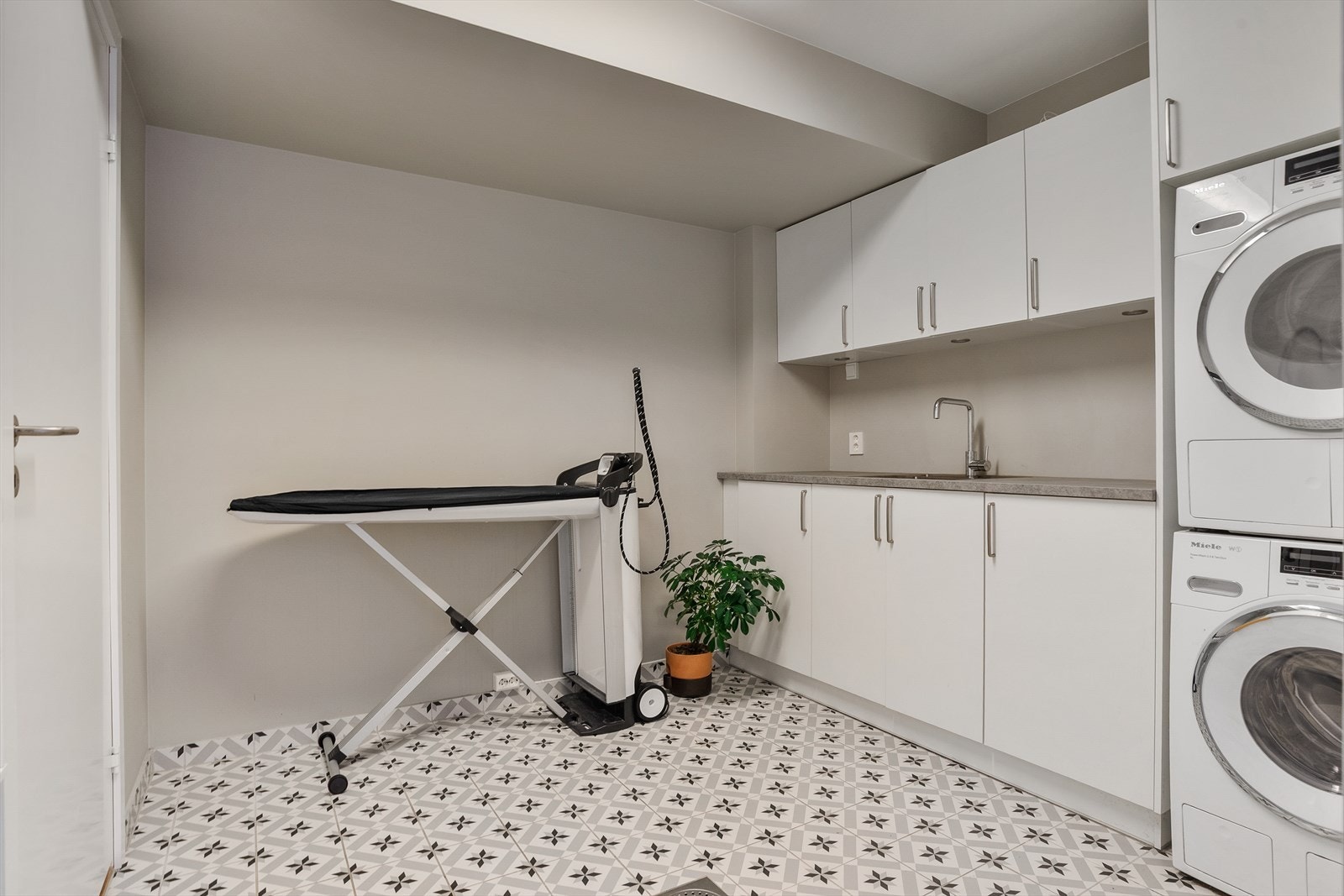 Vaskerommet i underetasjen har flislagt gulv og malte vegger, og er innredet med benk, nedfelt kum og gode oppbevaringsmuligheter. Det er opplegg for både vaskemaskin og tørketrommel. Galleribilde