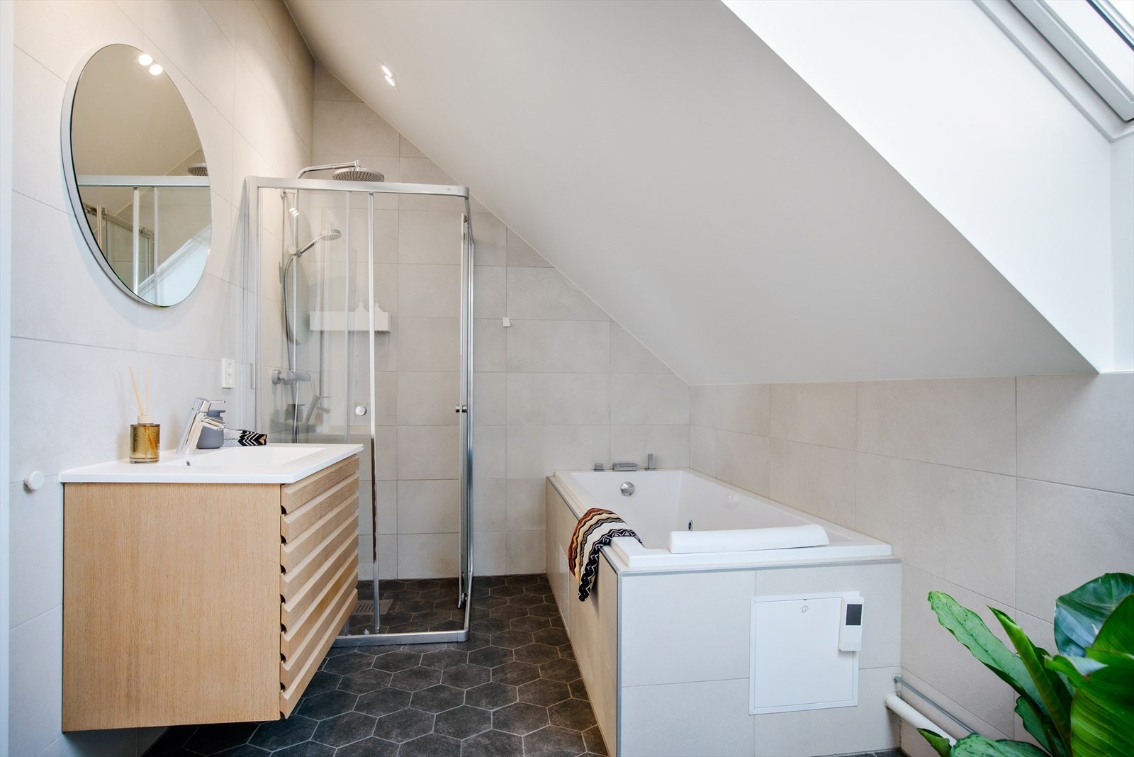 Bad i 2. etasje fremstår romslig og innbydende med flislagte overflater. Badet er innredet med dusjhjørne, innmurt boblekar, vegghengt toalett og servant i skuffeinnredning. Galleribilde