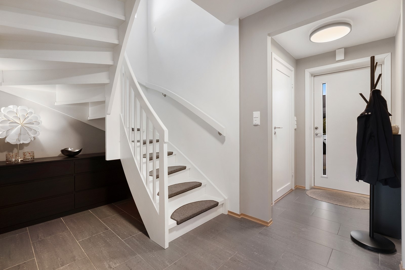 Velkommen inn til en lys og romslig flislagt entré. Det er god plass til oppheng for yttertøy og til å sette ifra seg sko, noe som gjør det enkelt å holde orden i inngangspartiet. Galleribilde