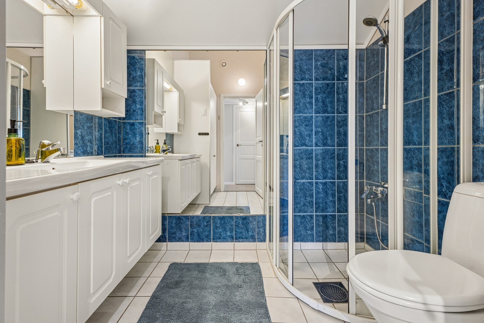 Badet har flislagt gulv samt vegger med kombinasjon av fliser og tapet. Galleribilde