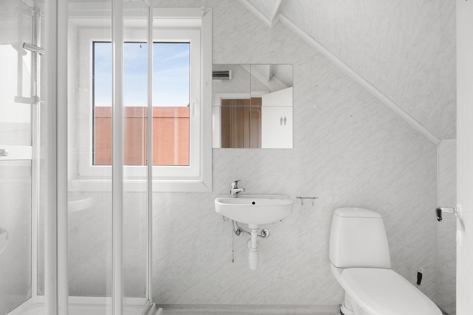 Lyst bad fra ca 2007 med baderomsplater på veggene, belegg på gulv og prefabrikkerte malte plater i himling - badet har behov for oppgradering for å tilfredsstille dagens krav til normal bruk Galleribilde