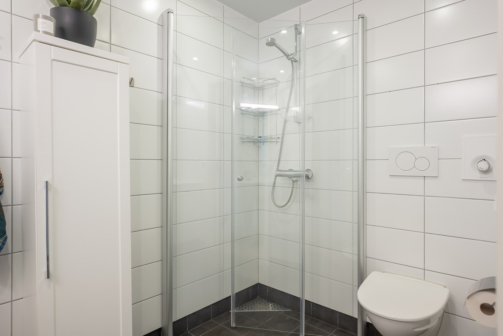 Badet er utstyrt med innfellbare dusjvegger, vegghengt toalett, høyskap og servantinnredning med gode oppbevaringsmuligheter. Galleribilde
