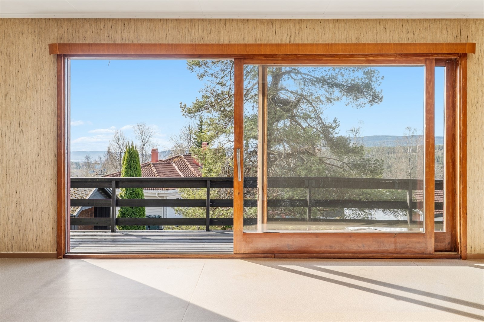 Utsikt fra stuen gjennom de store vinduene mot verandaen og nærområdet. Galleribilde