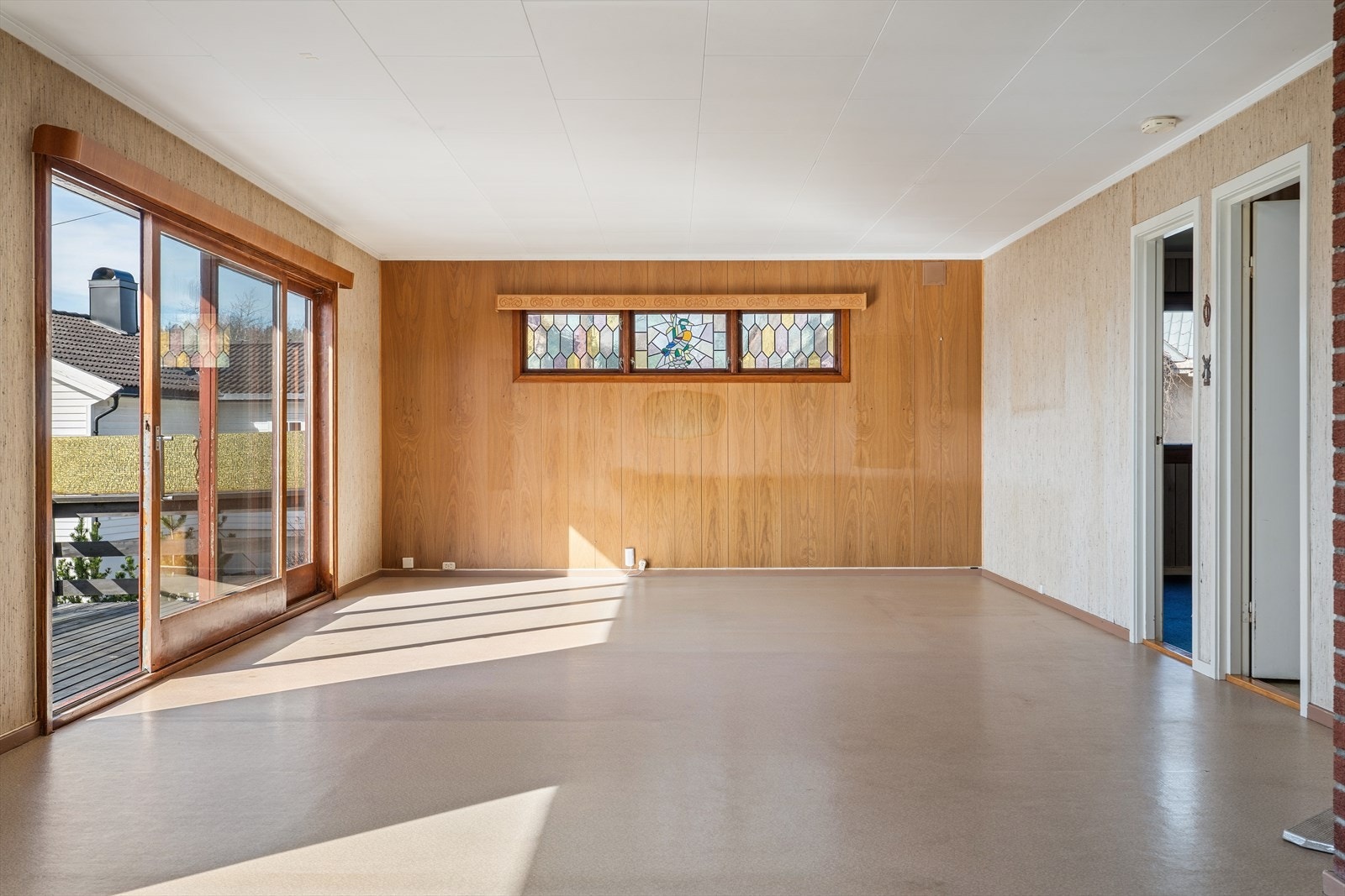 Stuen er romslig og har en fleksibel utforming som gir rom for ulike møbleringsløsninger. Skyvedøren i malt tre åpner opp mot verandaen. Galleribilde