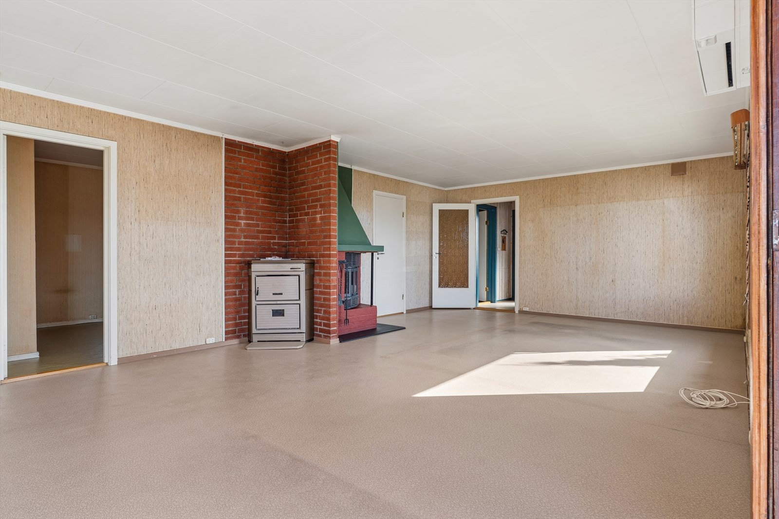 Stuen har vegger med strie og en fondvegg med teglstein, og belegg på gulvet. Galleribilde