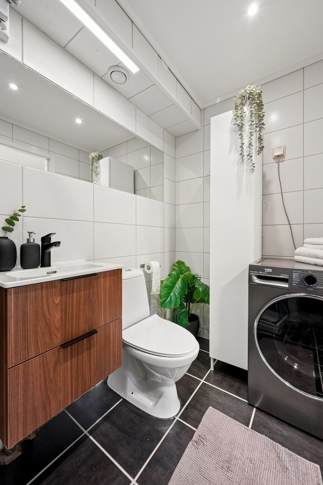 Badet ligger like ved og er lyst og praktisk innredet med dusjkabinett, toalett, servant og opplegg for vaskemaskin. Galleribilde