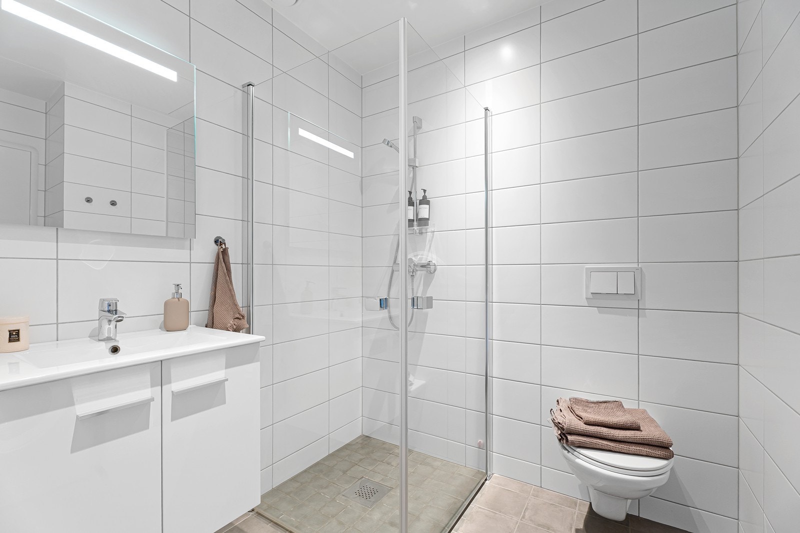 Badet er helfliset og innredet med dusjhjørne, vegghengt toalett og lekker servant. Galleribilde