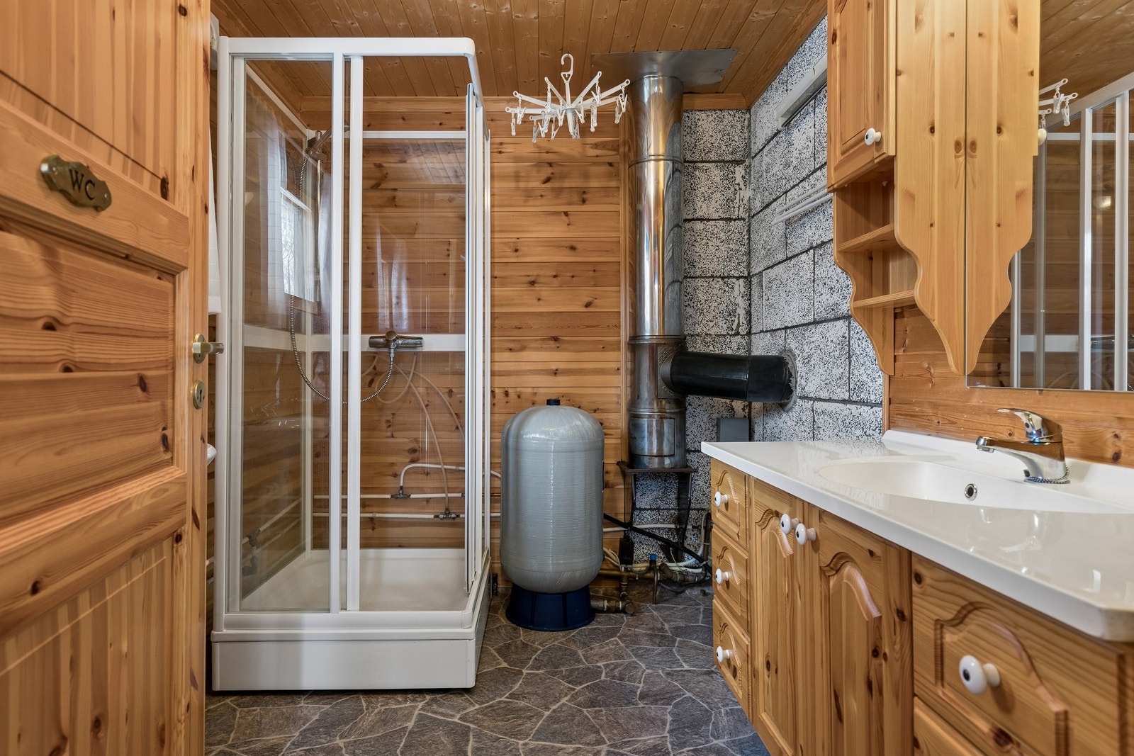 Badet er utstyrt med dusjkabinett og innredning med servant. Vanntanken til brønnsystemet er plassert her. Galleribilde