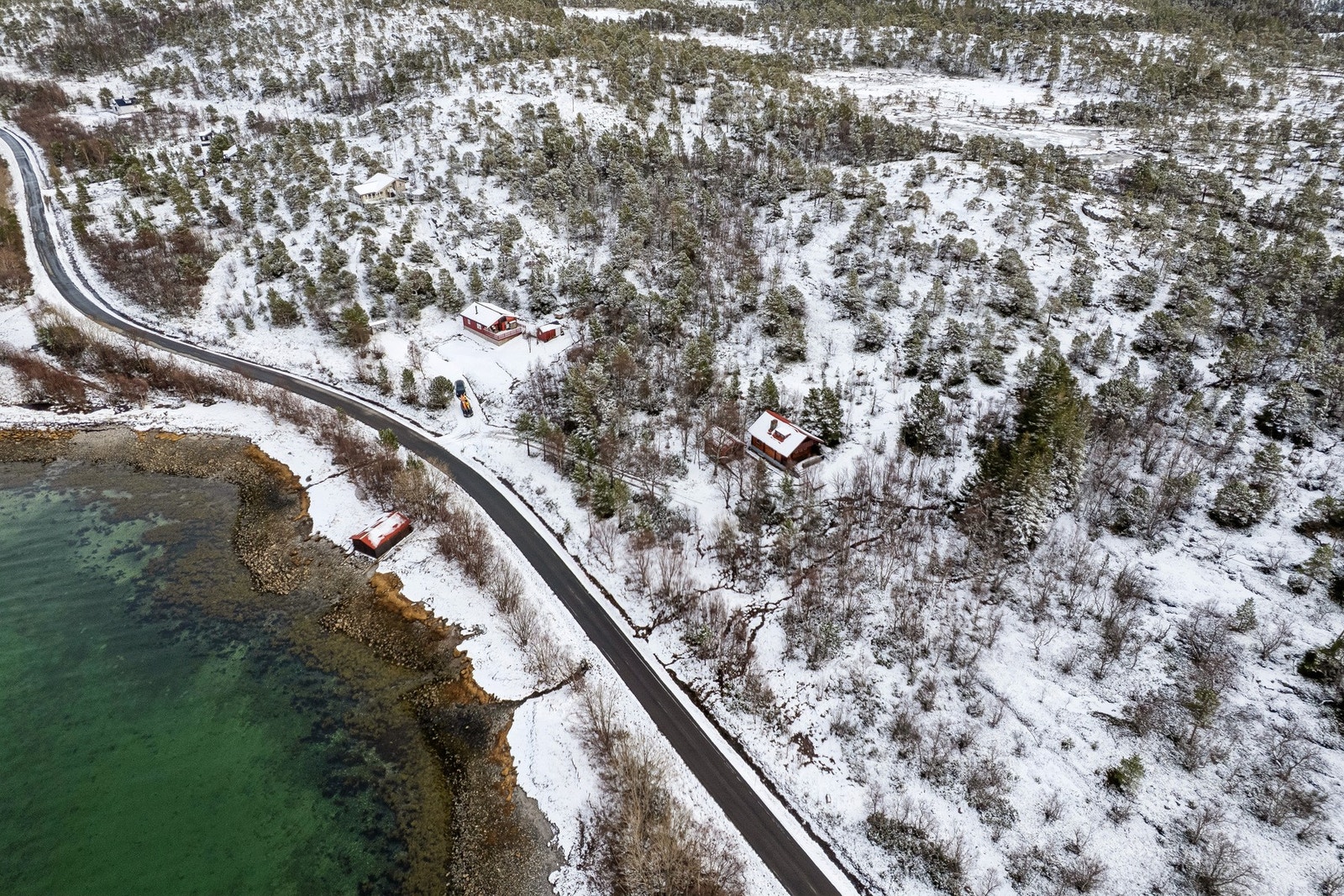 Oversikt som viser hyttas plassering i terrenget, med naustet nede ved sjøen. Galleribilde