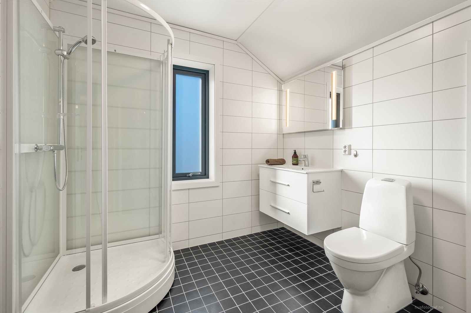 Pent bad i loftsetasjen med servantinnredning og speil. Badet er utstyrt med toalett og dusjkabinett. Galleribilde